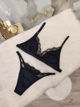 Conjunto de lencería compuesto por un corpiño triangular y una bombacha, ambos confeccionados en algodón negro con detalles de encaje en los bordes. El corpiño cuenta con breteles regulables y la bombacha presenta un diseño con tiras laterales.