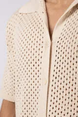 Camisa de manga corta tejida en algodón con diseño calado, cuello tipo bowling y cierre frontal con botones al tono.