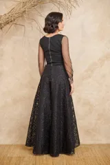 Blusa negra con cuerpo ajustado y mangas largas de tul transparente con puños decorados con lentejuelas.