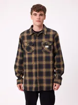 Camisa de manga larga confeccionada en franela de algodón, con diseño de cuadros en tonos verde y marrón. Presenta cuello clásico, cierre frontal con botones y dos bolsillos en el pecho con solapa.