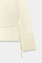Jersey de punto con cuello barco y manga larga. Presenta un diseño entallado en la cintura con un cinturón de perlas integrado y un bajo con volante.