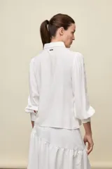 Camisa de manga larga color celeste, con cuello clásico y botonadura frontal. Presenta un calce relajado, con mangas amplias y puños anchos.
