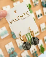 Aros tipo argolla de acero dorado con dije colgante de cristal facetado en color gris oscuro.