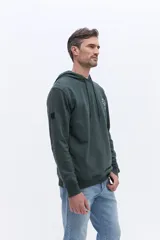 Canguro con capucha de algodón color beige, con cordones de ajuste y estampa circular frontal con el nombre de la marca y el año 1971.