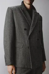 Blazer de corte relajado confeccionado en tejido con lana, con diseño de espiga. Presenta cuello con solapas de muesca, cierre frontal de botonadura cruzada, bolsillos de vivo en el pecho y bolsillos de solapa en la cadera.