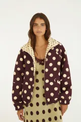Campera reversible con estampado de lunares, cuello alto, cierre frontal y bolsillos laterales.