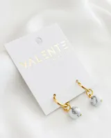 Aros colgantes con argolla dorada y dije esférico de piedra natural blanca con vetas grises.