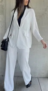 Pantalón blanco con finas rayas verticales negras, de corte palazzo y tiro alto.