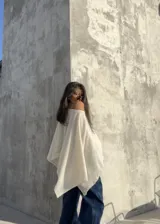 Poncho de hilo liviano en color crudo, con diseño sin cuello y caída fluida, ideal para media estación.