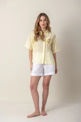 Camisa de mangas cortas con diseño color block en verde, blanco y rosa. Tiene un bolsillo con bordado de ave y flores bordadas en el frente.