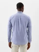 Camisa de popelina de manga larga con estampado de rayas verticales en color verde y blanco, cuello con botones y bolsillo frontal en el pecho.