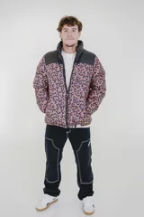 Campera puffer reversible con cuello alto y cierre frontal. Un lado presenta un diseño estampado animal print en tonos marrón y negro, mientras que el otro lado es de color negro liso. Cuenta con bolsillos laterales y ajuste elástico en los puños.