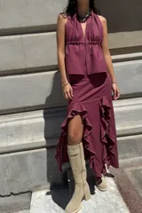 Conjunto de dos piezas color bordó, compuesto por un top halter con escote en V y ajuste elástico en la cintura, y una falda midi con volados laterales y terminaciones desflecadas.