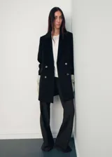 Abrigo midi de doble botonadura en color negro, confeccionado en mezcla de lana. Presenta cuello con solapas de muesca, manga larga y dos bolsillos laterales con solapa.