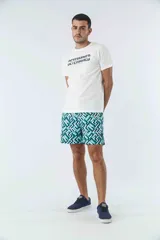 Short de baño con estampado geométrico en tonos verdes y azules, con bolsillos laterales y bolsillo posterior. Cuenta con logo en goma y está confeccionado en tela ligera de secado rápido.