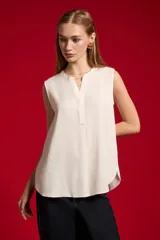 Blusa evasé de viscosa color blanco, sin mangas, con cuello a la base y escote en V con cartera frontal.