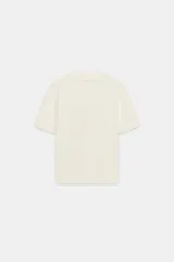 Top de punto color crudo, con cuello polo y escote en V. Cuenta con mangas cortas y detalle de puntilla con forma de onda en el cuello y los puños.