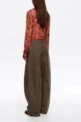 Camiseta de manga larga confeccionada en tejido de tul semitransparente con estampado animal print abstracto. Presenta cuello redondo, corte ajustado y detalles de frunces laterales que aportan textura y movimiento a la prenda.