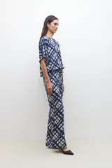 Pantalón acampanado con estampado abstracto en tonos azul marino y beige, con cintura elastizada y cordón ajustable.