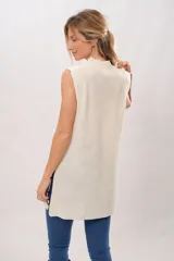 Chaleco largo color crema de tejido de punto con cuello alto y sisas amplias. Presenta un diseño de líneas negras irregulares en los bordes.