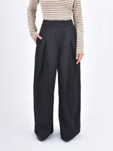 Pantalón de vestir negro de corte wide leg, con pinzas frontales y cintura alta.