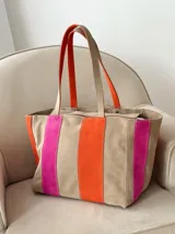 Cartera tipo bolso shopper de cuero y gamuza, con diseño de rayas verticales en tonos beige, fucsia y naranja, y doble asa de hombro.