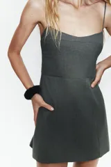 Vestido corto de corte ajustado con escote tipo corset y tirantes finos. Presenta costuras verticales que definen la silueta y cierre posterior oculto.
