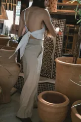 Pantalón de corte recto y tiro alto, confeccionado en lino color blanco. Presenta cierre frontal con botón y bolsillos laterales.