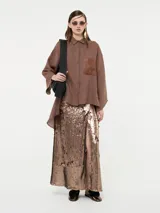 Falda midi negra cubierta de lentejuelas, con tajo frontal y corte recto.