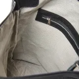Mochila de cuero negro con textura granulada, diseño versátil con manija superior para llevar al hombro y cierre frontal vertical con cremallera. Incluye placa metálica con logo de la marca.