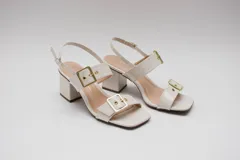 Sandalias de tacón ancho color crema, con acabado acharolado y doble hebilla dorada.
