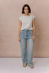 Pantalón de jean estilo wide leg con tiro medio-alto, lavado azul medio con efecto desgastado, diseño de cinco bolsillos y cierre frontal con botón y cremallera.