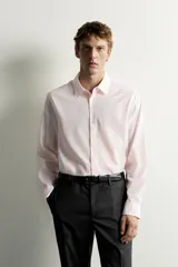 Camisa de corte regular fit color rosado pálido, con cuello solapa, manga larga y cierre frontal de botones.