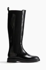Botas de caña alta negras de cuero sintético, con diseño tipo Chelsea de punta redondeada, paneles elásticos laterales y tirador trasero.
