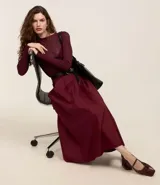 Pollera evasé midi color borgoña, confeccionada en tricolina de algodón sostenible, con tiro alto, pliegues delanteros y cierre trasero por cremallera.