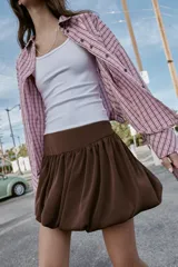 Falda corta de tiro alto con diseño abullonado tipo globo, confeccionada en tejido satinado de color marrón con cierre lateral oculto.