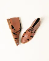 Zapato acordonado de cuero vacuno color marrón con aberturas laterales y cordones negros.