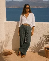 Pantalón de lino color verde oscuro, de corte ancho y relajado, con cintura elástica y cinto de rafia con hebilla redonda.