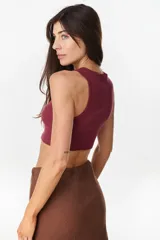Musculosa de algodón en color bordó, de corte corto, con cuello redondo y detalles de flores decorativas aplicadas en el pecho.