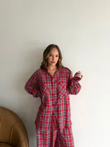 Camisa de corte oversize confeccionada en viyela con estampado de cuadros escoceses en tonos rojo, negro y blanco. Presenta cuello clásico, cierre frontal con botones, mangas largas y dos bolsillos delanteros con solapa.