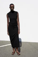 Falda midi de tiro medio en color negro, confeccionada en tejido de punto con textura y cintura elástica ajustable con cordones.