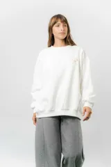 Buzo oversize de algodón frizado color blanco, con cuello redondo y puños y cintura tejidos. Presenta un bordado pequeño de Snoopy en el pecho.