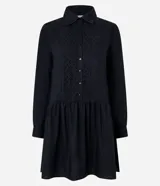 Vestido corto de corte evasé confeccionado en tricolina de algodón, color azul. Presenta cuello camisero, cierre frontal de botones y un panel central con detalle bordado calado. Posee mangas largas con puños abotonados.