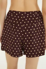 Falda pantalón corta de silueta recta en color marrón con estampado de lunares blancos y detalles sutiles de la marca. Presenta un diseño cruzado en el frente y cierre lateral con botón.
