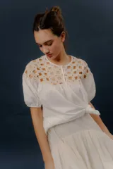 Blusa blanca de algodón con detalles de crochet en la parte superior y mangas cortas abullonadas.