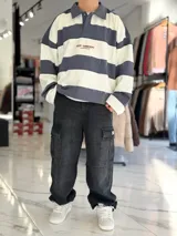 Buzo polo de rayas horizontales en gris oscuro y blanco, con cuello camisero, cierre frontal parcial y corte oversize. Presenta un gran número 88 estampado en la espalda en color bordó junto con la inscripción VCP/ARG.