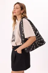 Bolso tipo hobo de símil cuero negro, con diseño de apliques metálicos circulares en todo el frente y manija integrada.