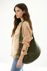 Camisa blanca de tela liviana y ligeramente arrugada, con bordados de motivos marinos en tonos azul, verde y ocre. Presenta cuello camisero, abotonadura frontal y mangas tres cuartos.