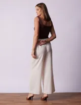 Pantalón largo de poliéster color beige con rayas verticales, pretina ancha elastizada en punto smock y pierna ancha.