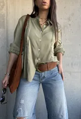 Camisa de manga larga color verde militar con inserciones de encaje decorativo en el frente y las mangas, cuello camisero y cierre frontal de botones.